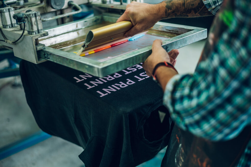 Male worker pressing ink on frame while using the printing machi